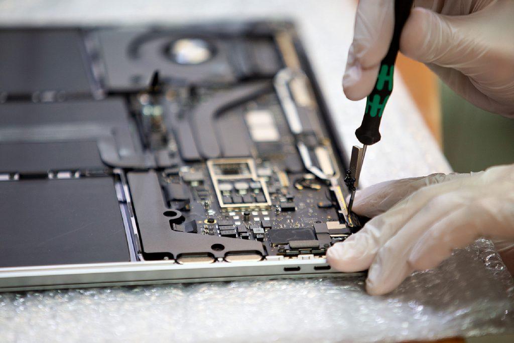Fachmann löst eine Schraube, um das Logicboard auszutauschen Fachmann löst eine Schraube, um das Logicboard auszutauschen